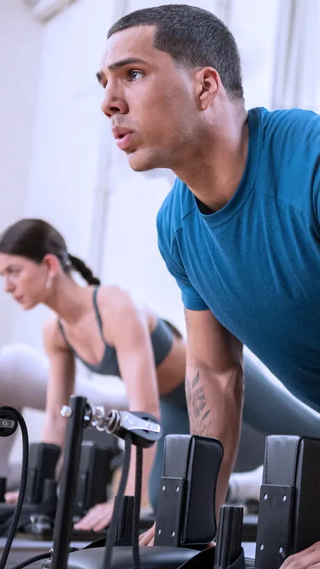Man and Woman using pilates Reformers for fitness training.