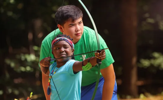 CILT staff helping a child learn archery