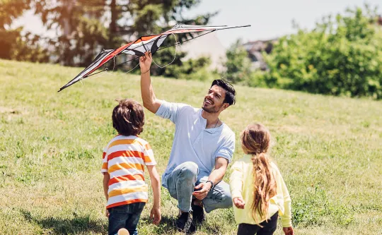 Father with two kids flying a kite