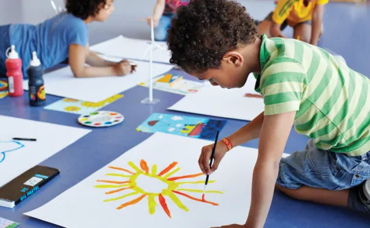 Group of kids painting artwork on the floor at Parents Night Out