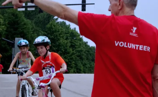 Adult Volunteer directing youth participants in a triathlon