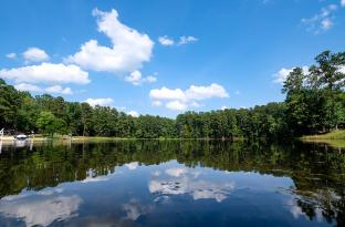 The lake at YMCA Camp Kanata, mirror still, reflecting green pine trees on both sides