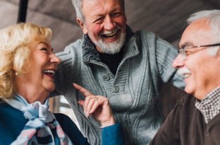 Older adults gathering around a table for conversation in a well lit room