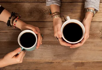 hands holding coffee cups at a table