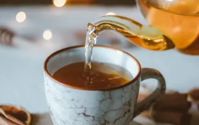 Porcelain tea cup on a table of white linen with twinkling lights in the background