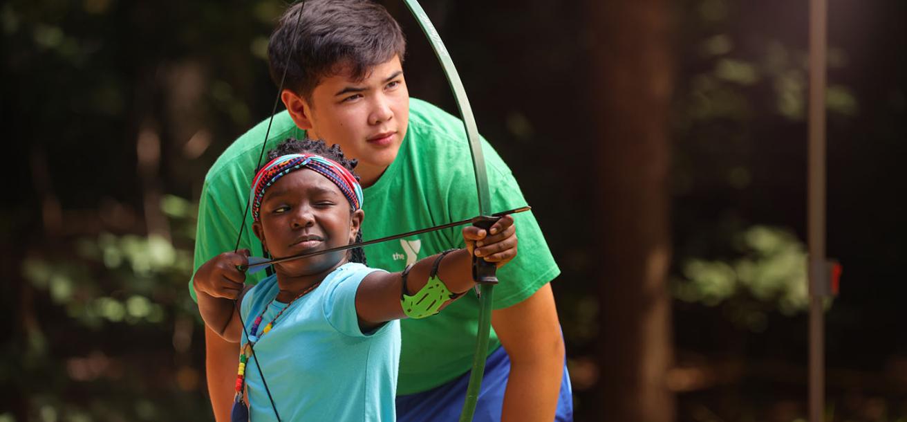CILT staff helping a child learn archery